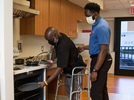 Male patient practices using an oven while on his walker.
